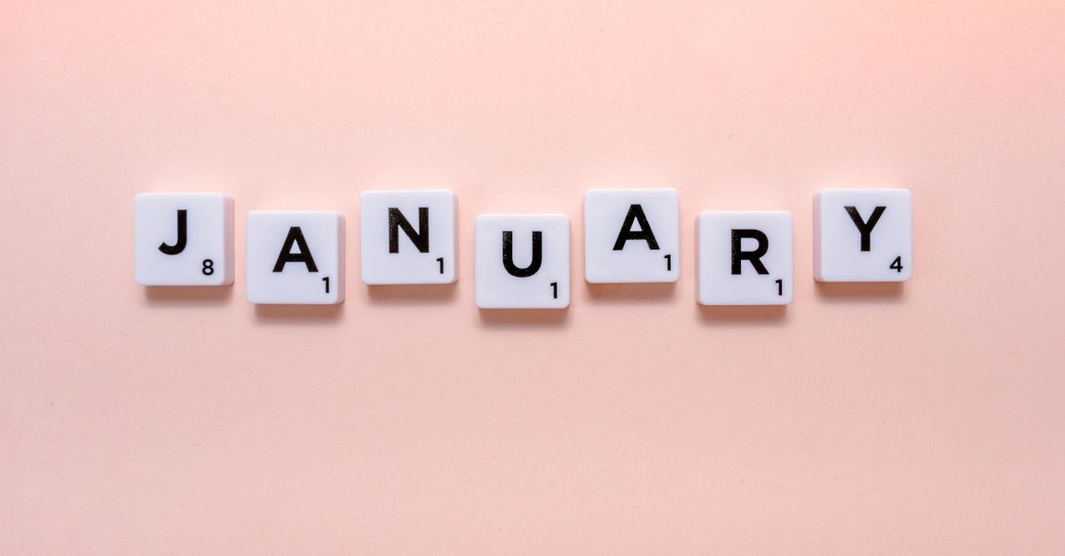Scrabble tiles spelling 'January' on a soft peach background, perfect for new year themes.